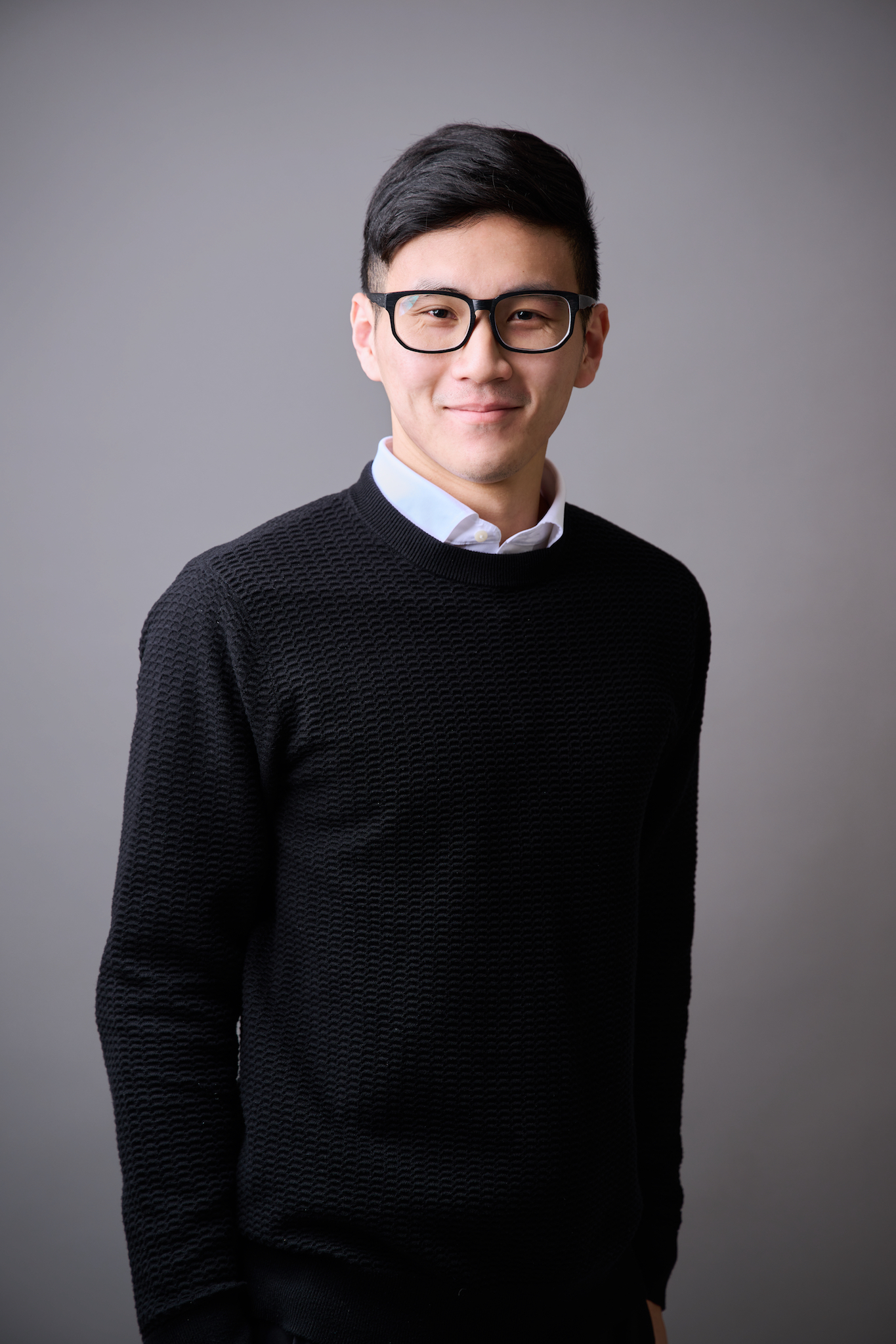 台南專業形象照推薦：親切男性商務形象攝影。穿著黑色針織衫與襯衫，戴黑框眼鏡，展現自信微笑。適合求職、社群頭像或個人品牌經營。