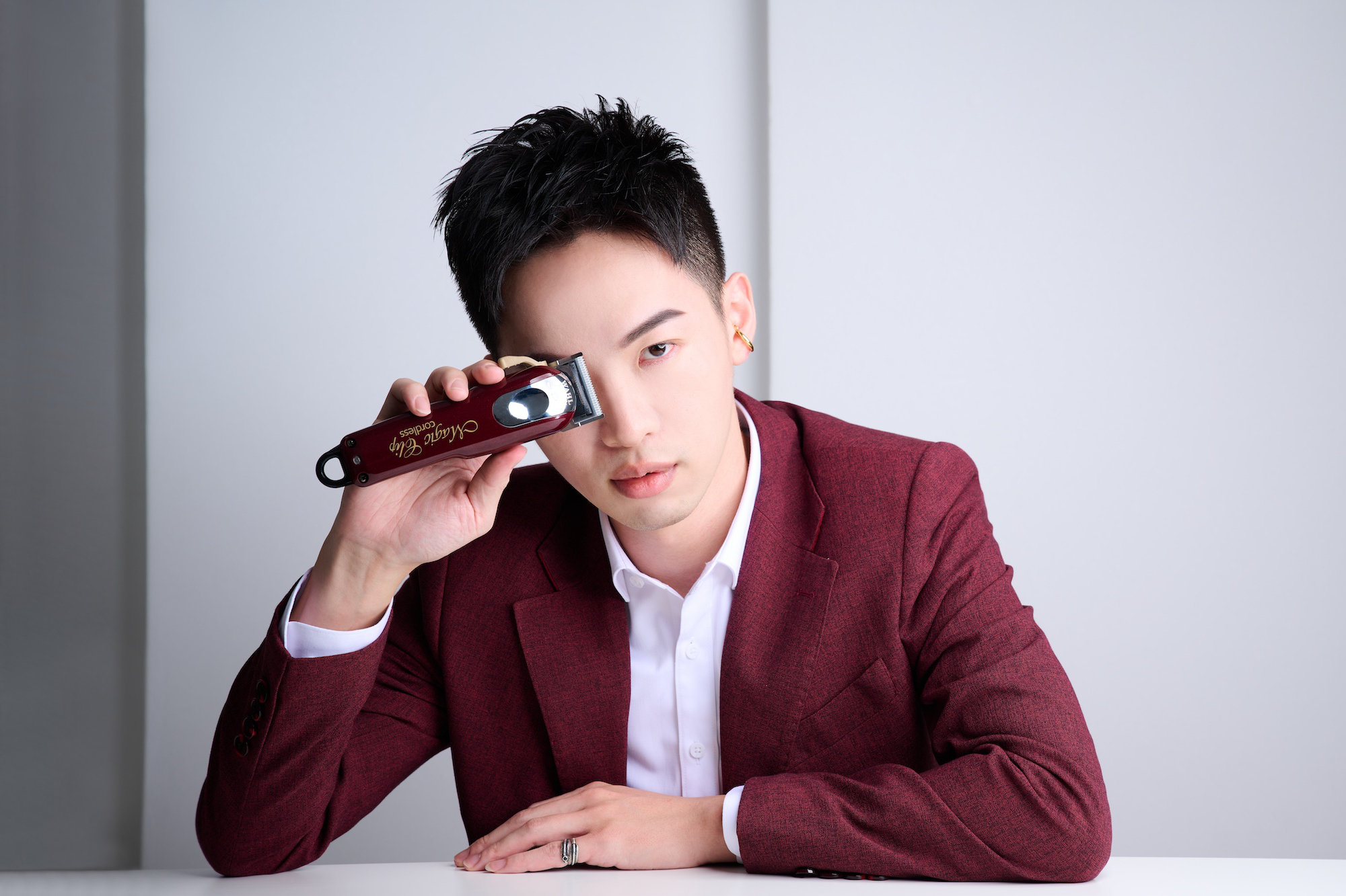 男性理髮師專業形象，搭配理髮電剪與西裝外套配色，達成畫面專業的一致性。