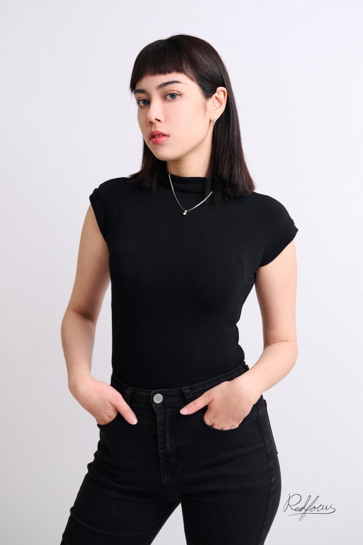 台南個性形象照推薦：現代極簡風格女性肖像。模特兒身穿黑色高領短袖合身上衣，雙手自然插入口袋，展現冷靜專業的氣場與俐落短髮造型，適合創意產業主理人、技術職人與社群經營者。