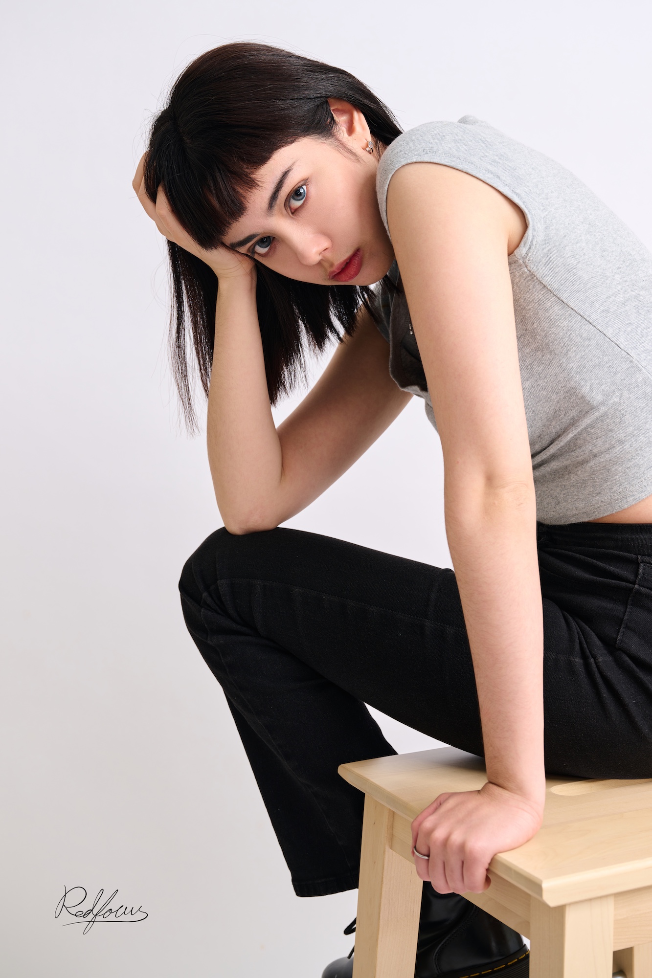 台南形象照推薦：個性時尚風格女性攝影。模特兒身穿灰色合身背心與黑色長褲，俐落短髮搭配手扶頭的側坐姿勢，展現冷艷且具張力的視覺美感。適合演藝人員形象、時尚品牌宣傳與高品質個性化寫真。