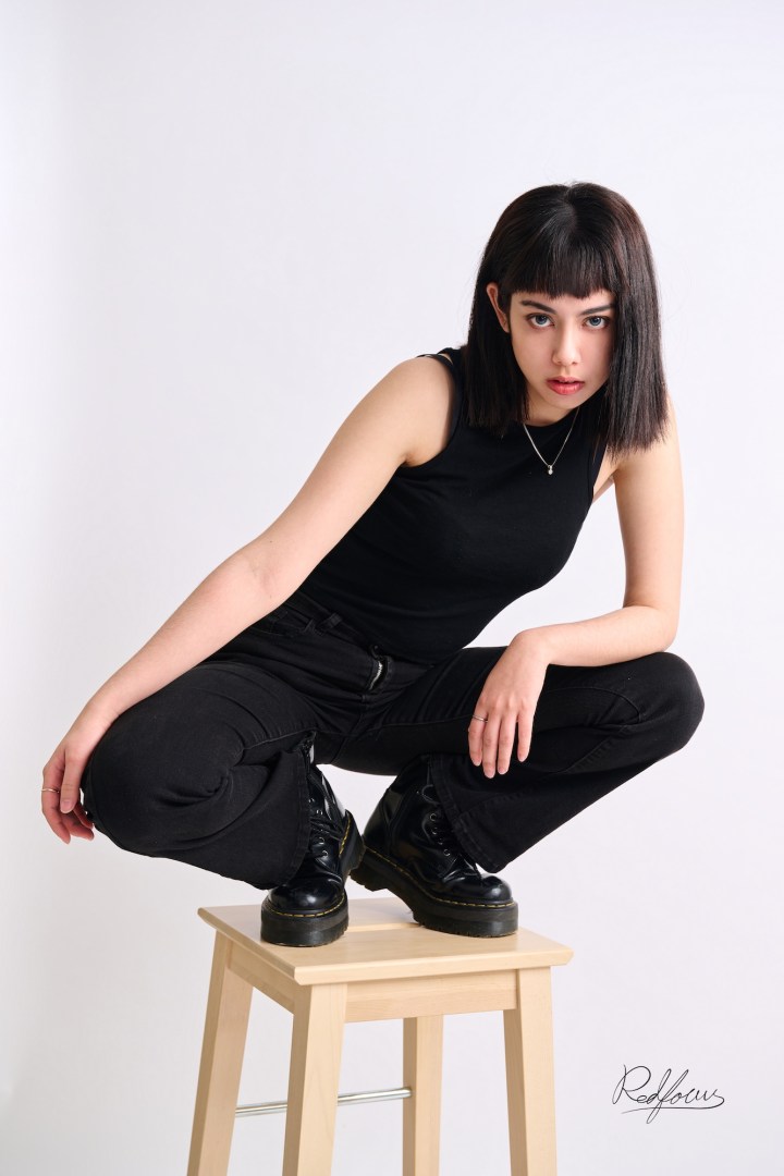 台南形象照推薦：潮流個性風格女性全身攝影。模特兒身穿全黑背心、牛仔褲與馬汀靴，以獨特蹲姿展現強烈街頭感與俐落短髮造型，適合演藝經紀、潮流品牌經營與個性個人寫真。