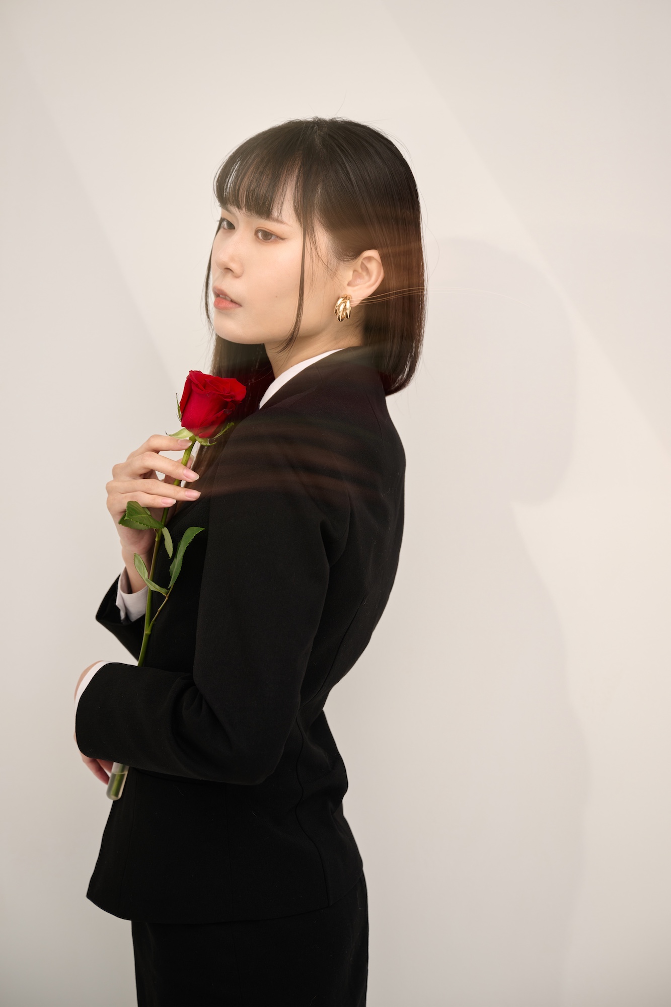 台南形象寫真：女性身穿深色西裝手持紅玫瑰，展現光影流動的藝術感與內斂特質。適合個人品牌美學、藝術攝影作品集及社群媒體視覺形象展示。