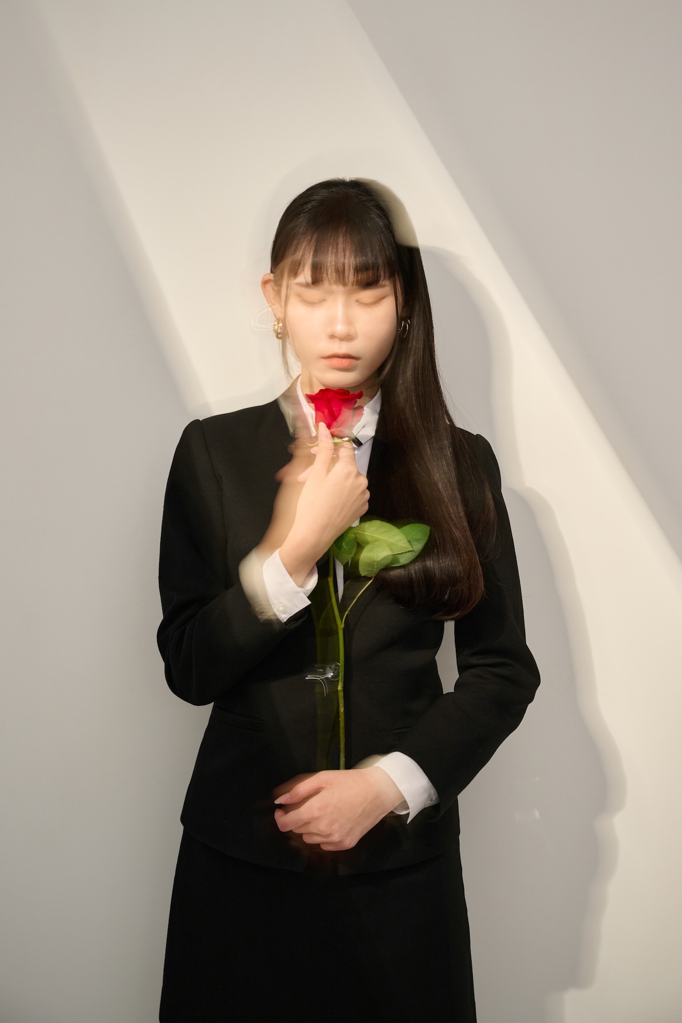 台南形象寫真：女性身穿俐落西裝與鮮紅玫瑰，眼神深邃且自信，展現優雅與知性並行的神韻。適合用於個人品牌頁面視覺、藝術感個人簡介或強調美學品味的職人專欄。