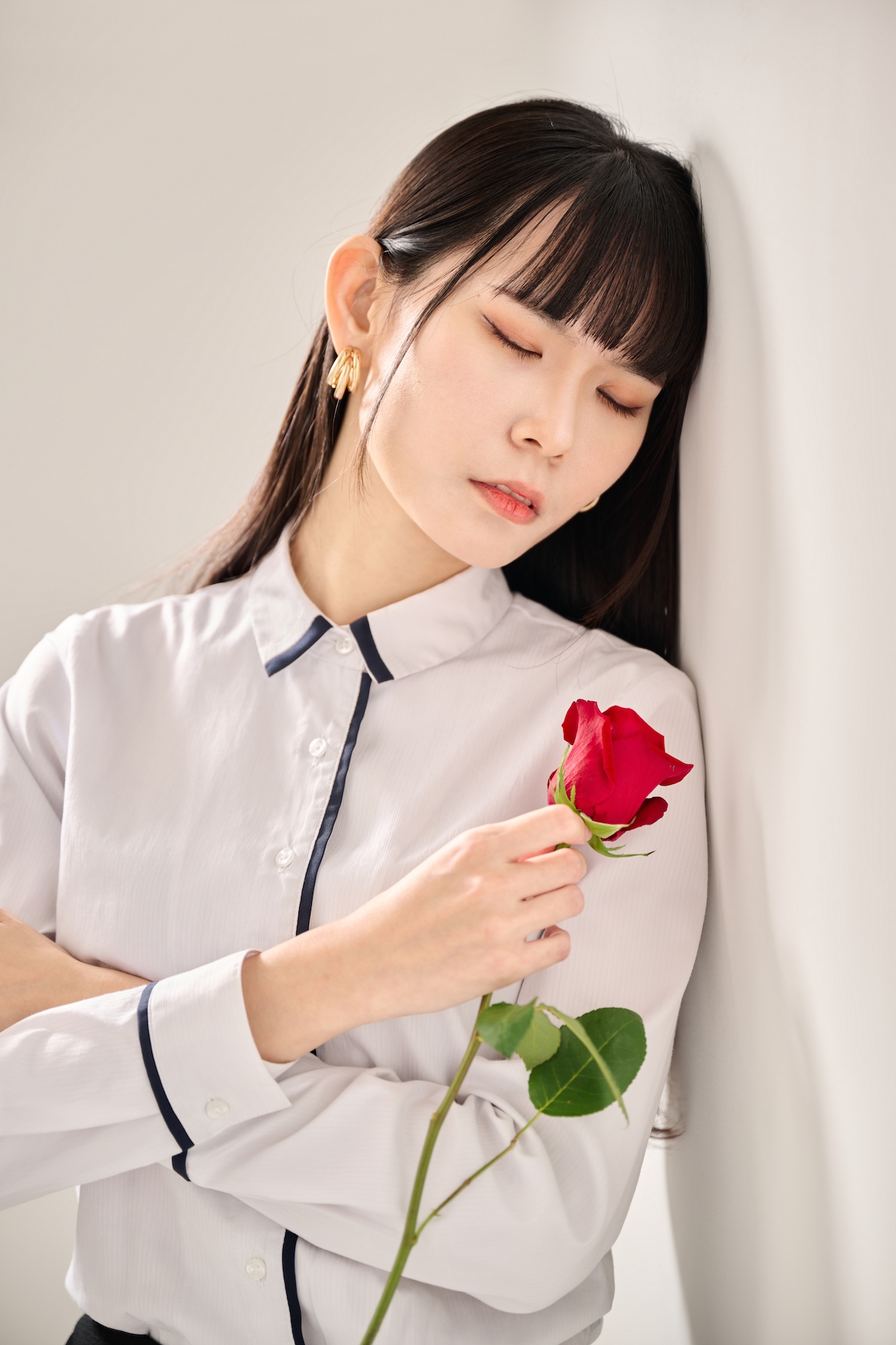 台南形象寫真：知性女性輕靠牆面並閉上雙眼，懷抱紅玫瑰展現安詳寧靜的神韻。適合個人品牌感性故事、心理成長專欄或強調內在質感的視覺頁面。