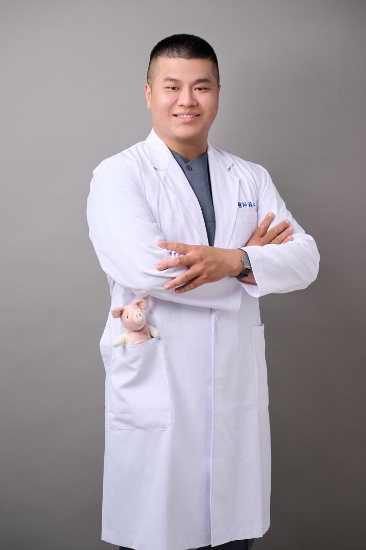 台南中醫師形象照推薦：蒔見中醫醫師展現自信抱胸姿勢，結合口袋公仔設計，呈現專業且溫暖的現代中醫形象。適合診所品牌牆、個人簡介與衛教文宣。