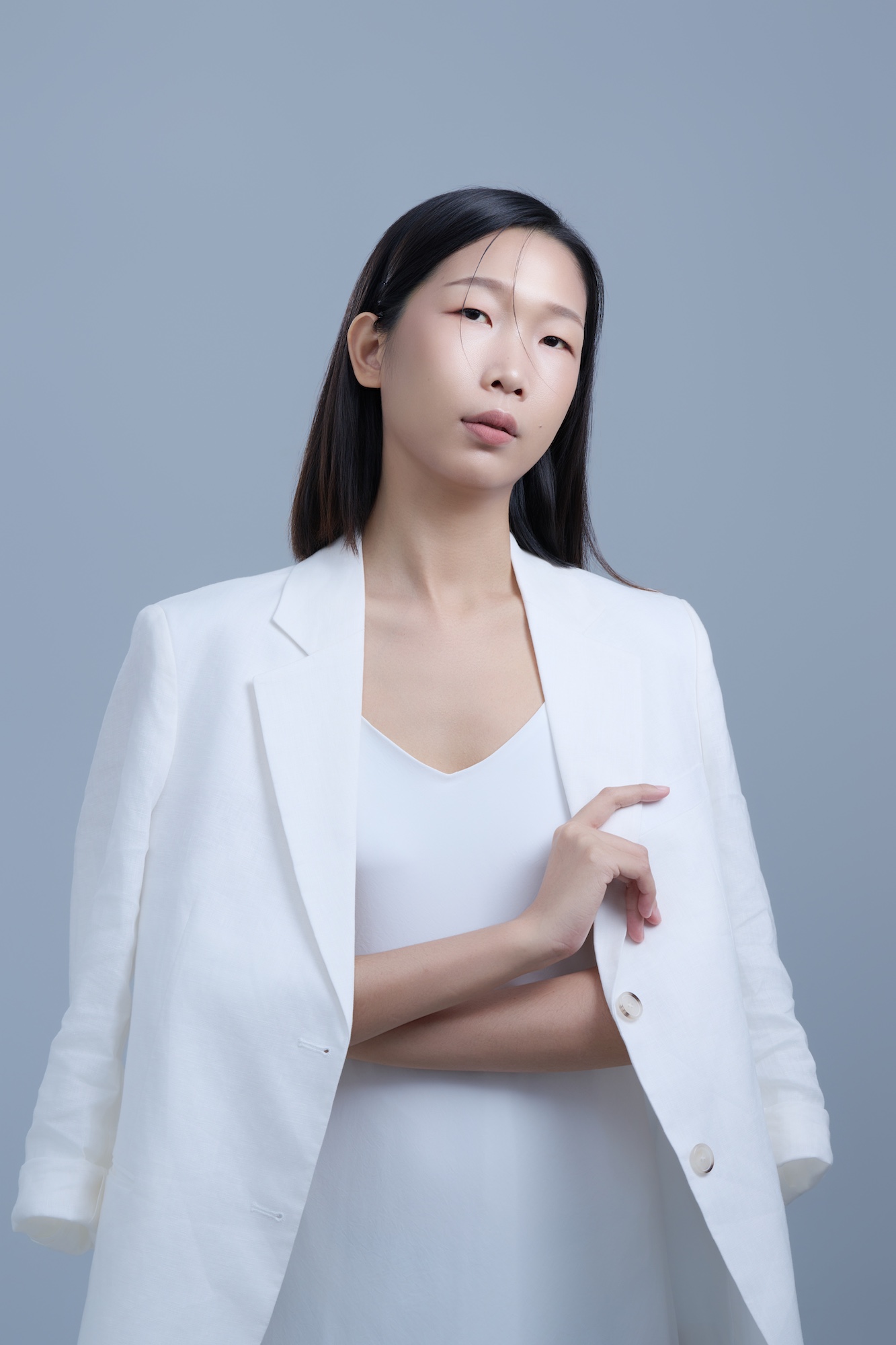 台南形象照推薦：專業彩妝師與造型師品牌肖像。模特兒身穿純白西裝外套，展現幹練、沉穩且具備高度美感的神韻。淡灰色簡約背景突顯職人氣質，適合新秘團隊介紹、美學講師與品牌宣傳使用。