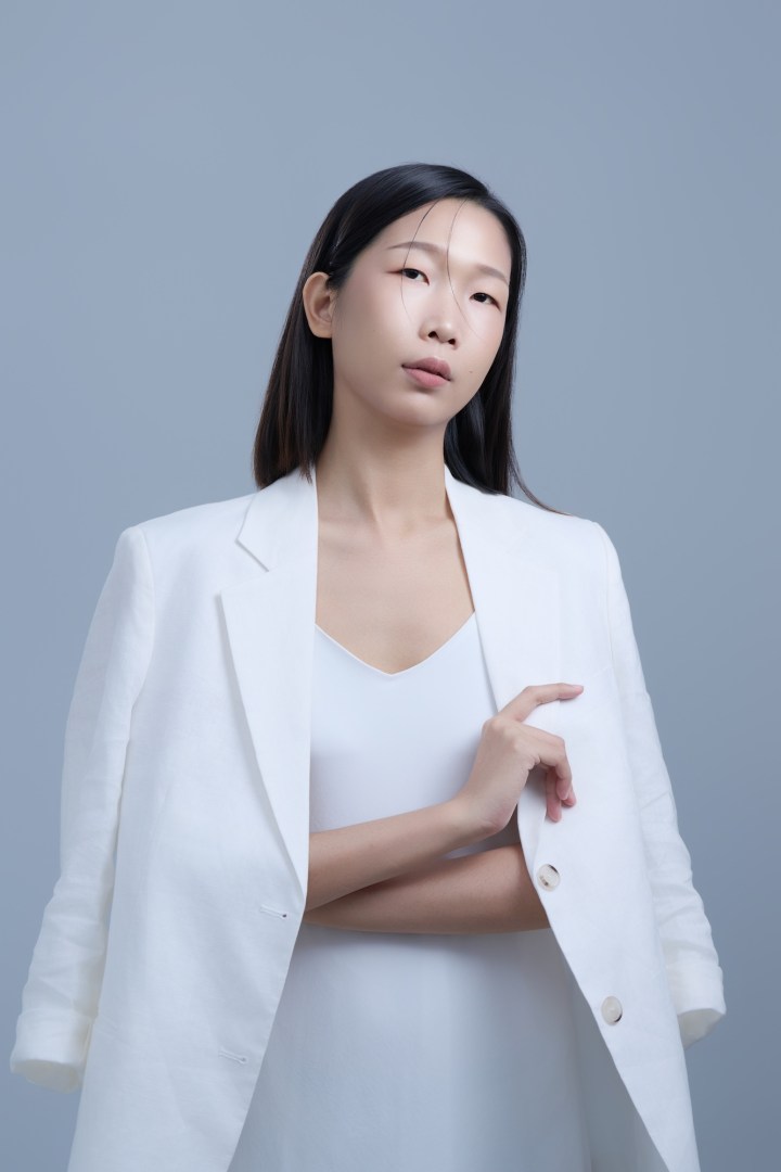 台南形象照推薦：專業彩妝師與造型師品牌肖像。模特兒身穿純白西裝外套，展現幹練、沉穩且具備高度美感的神韻。淡灰色簡約背景突顯職人氣質，適合新秘團隊介紹、美學講師與品牌宣傳使用。