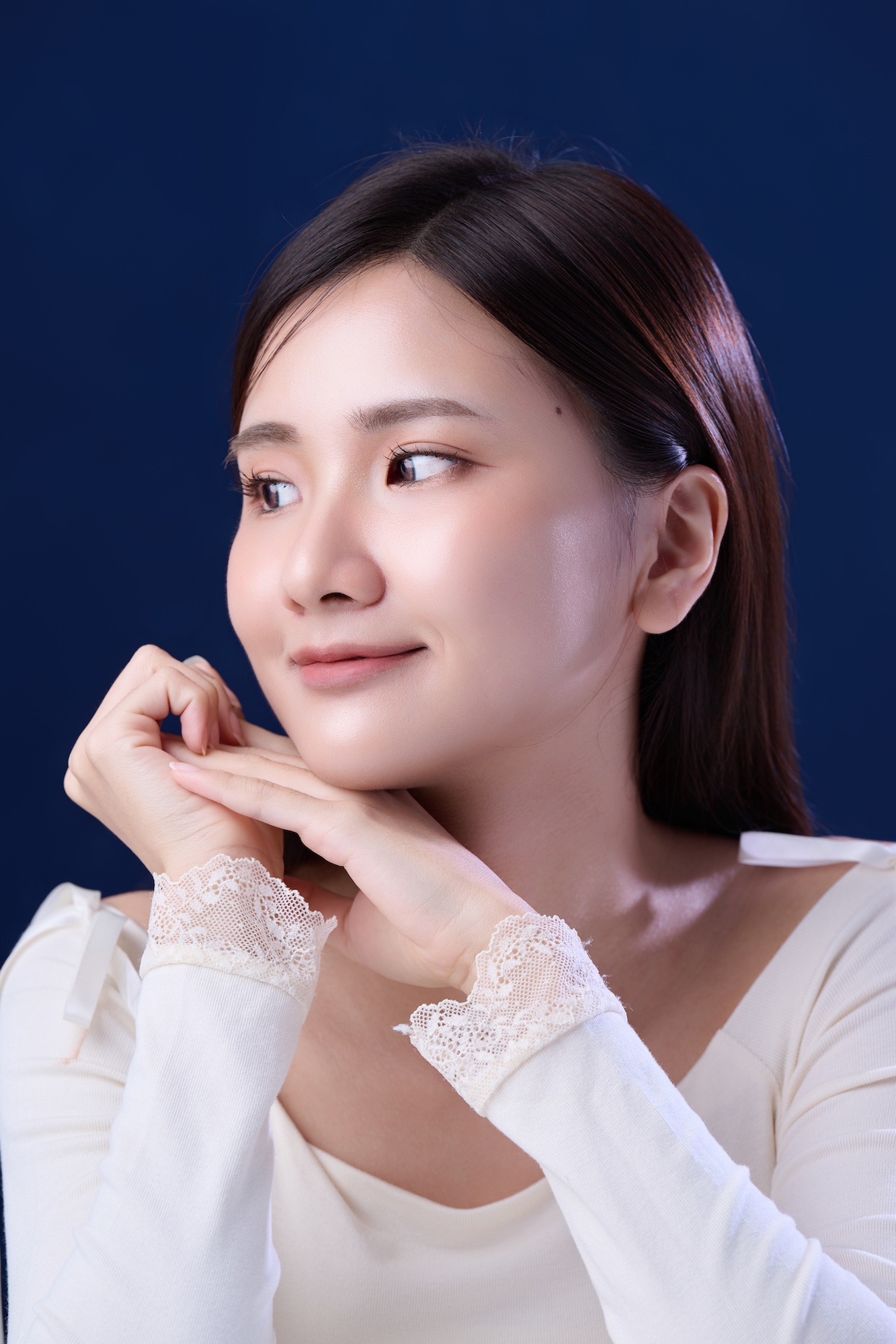 台南形象照推薦：溫柔生活感女性肖像攝影。長髮女性側頭微笑，展現自然親和力與細緻蕾絲袖口細節。深藍色背景營造高品質感，適合個人部落格與品牌宣傳。