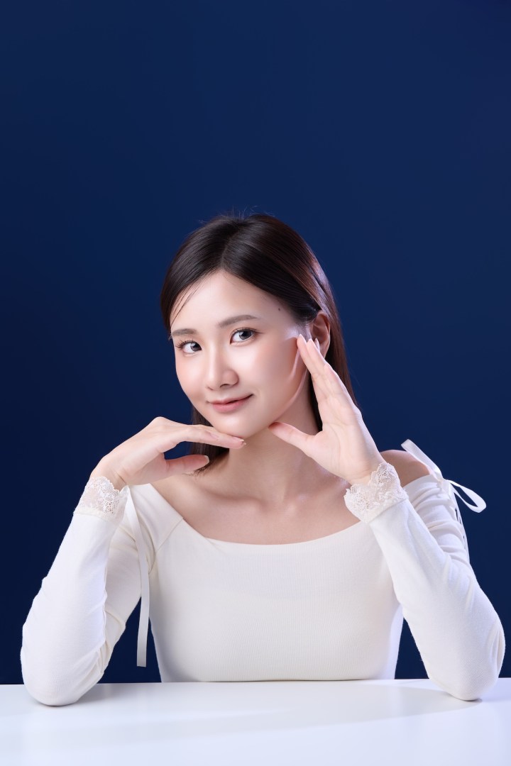 台南形象照推薦：知性商務風格女性攝影。身穿白色平口上衣搭配蕾絲袖口，展現親切微笑與專業儀態。深藍背景與質感打光，適合個人品牌經營、社群頭像與履歷照。