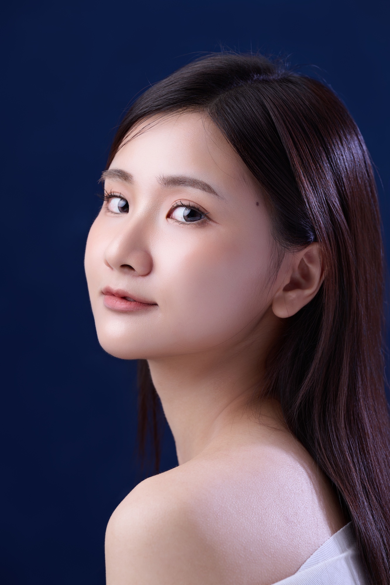 台南形象照推薦：韓系清透風格女性肖像。深藍色背景突顯通透膚質與細膩光影，展現溫柔且精緻的個人魅力，適合個人品牌、演藝形象照與社群頭像。