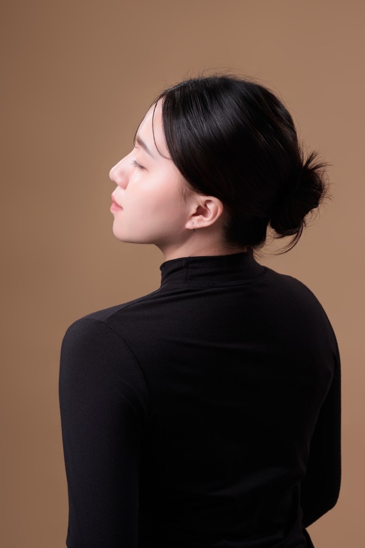台南形象照作品：大地色系女性閉眼知性肖像。在溫潤光影下展現寧靜優雅氣息，黑色高領與盤髮造型襯托側臉線條，適合瑜伽、諮商、美學職人形象與高品質個人寫真。