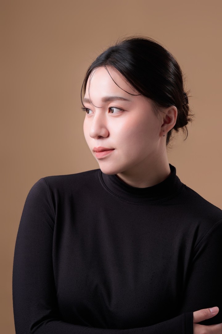 台南形象照推薦：大地色背景女性知性形象攝影。黑色高領上衣搭配優雅盤髮，側面視角展現沉穩氣質與自然妝感，適合專業職人、講師與個人品牌頭像。