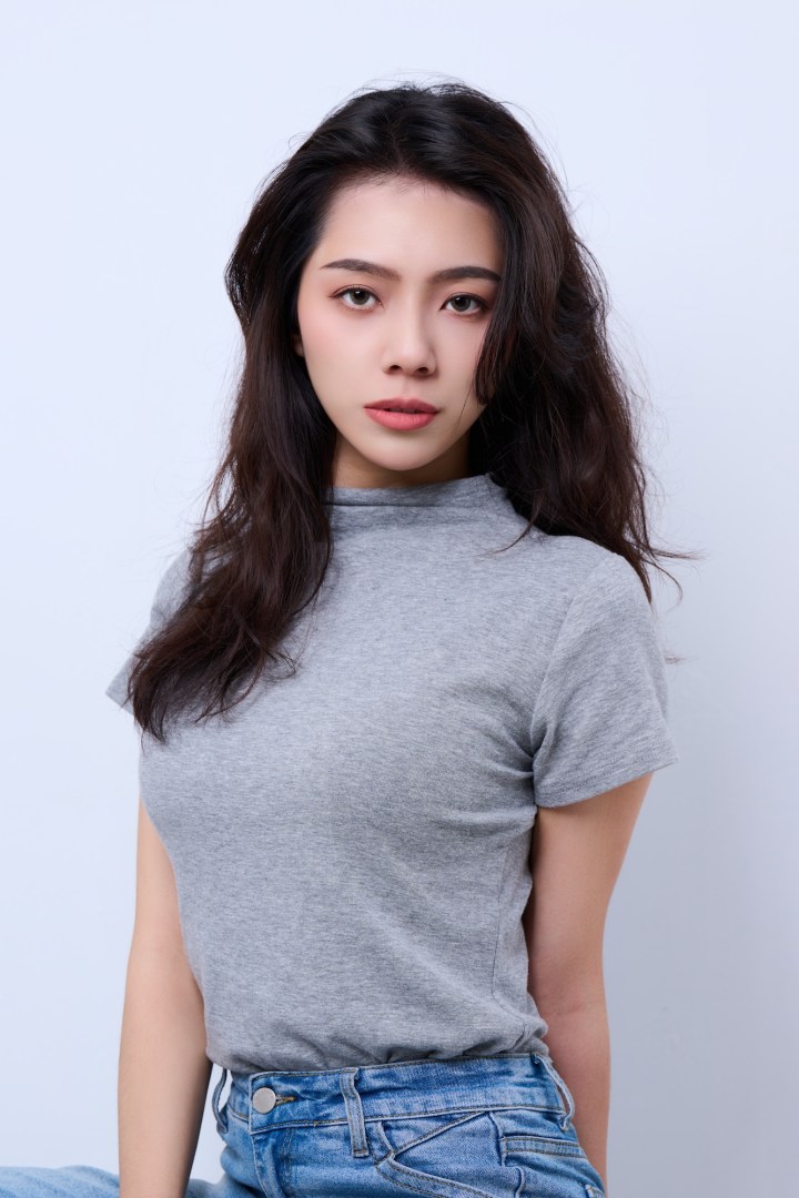 台南形象照推薦：女性優雅商務形象攝影。長捲髮女性面帶自信微笑，精緻妝感搭配簡約灰色服裝，展現知性親和與專業感，適合社群名片與個人品牌頭像。