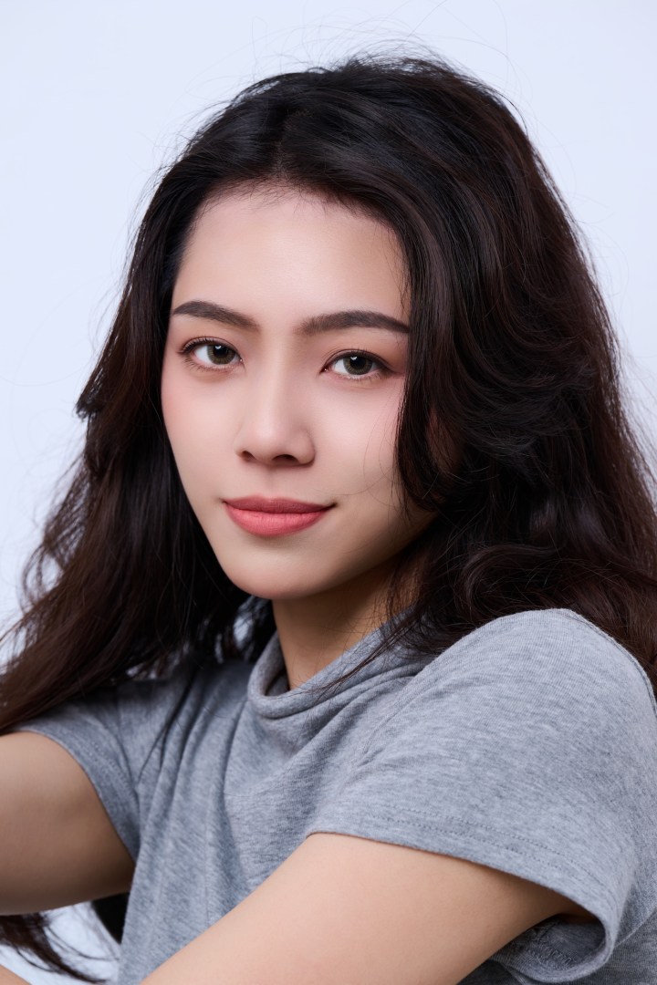 台南形象照推薦：女性優雅商務形象攝影。長捲髮女性面帶自信微笑，精緻妝感搭配簡約灰色服裝，展現知性親和與專業感，適合社群名片與個人品牌頭像。