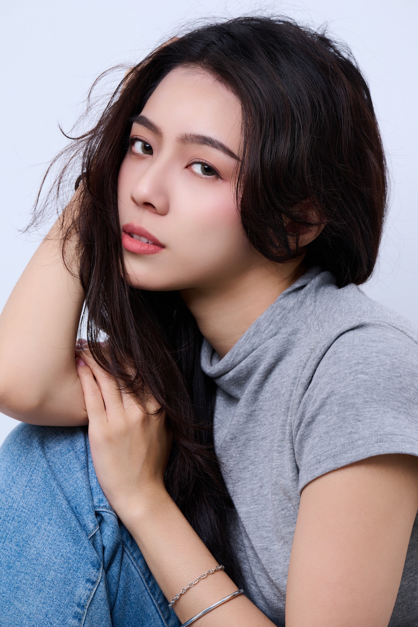 台南形象照推薦：女性精緻特寫肖像。深色捲髮模特兒展現迷人眼神，清新妝容與淺灰色背景交織出高質感氛圍。適合模特兒試鏡、演藝頭像與個人形象寫真。