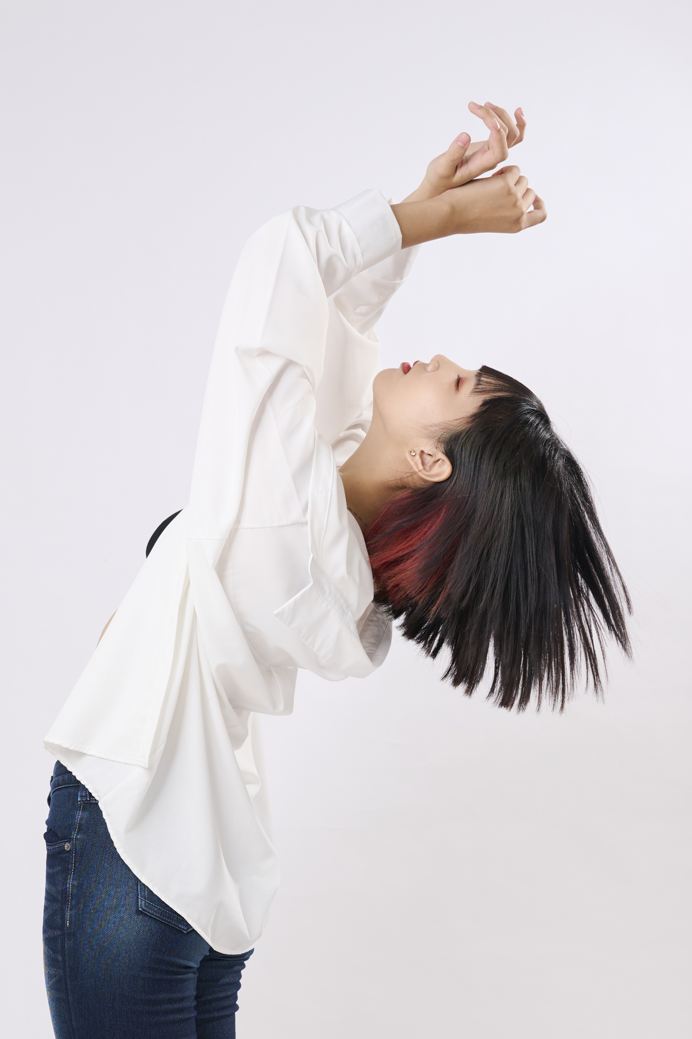 台南形象照推薦：藝術感個人形象攝影。捕捉女性紅黑挑染短髮的動態瞬間，搭配純白背景與白襯衫，展現強烈個人品牌特色與肢體表現力。