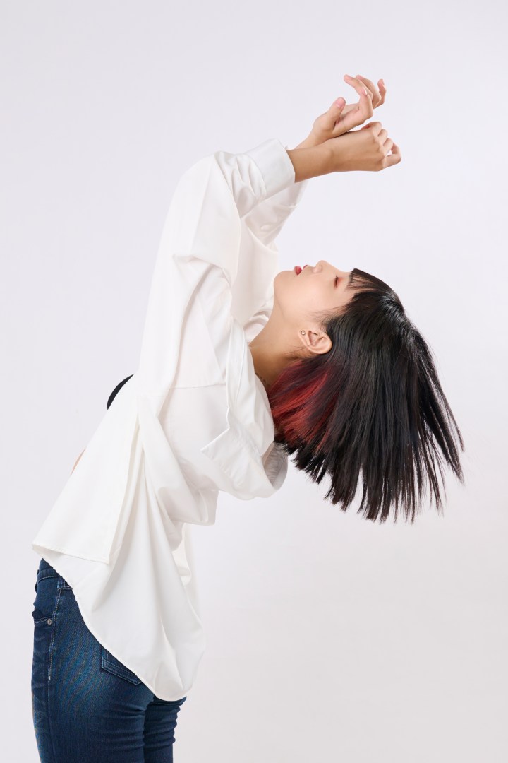 台南形象照推薦：藝術感個人形象攝影。捕捉女性紅黑挑染短髮的動態瞬間，搭配純白背景與白襯衫，展現強烈個人品牌特色與肢體表現力。